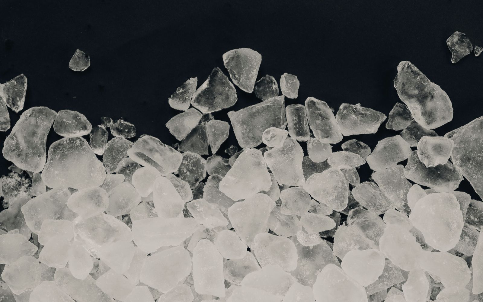 Overhead view of broken ice over dark ground.