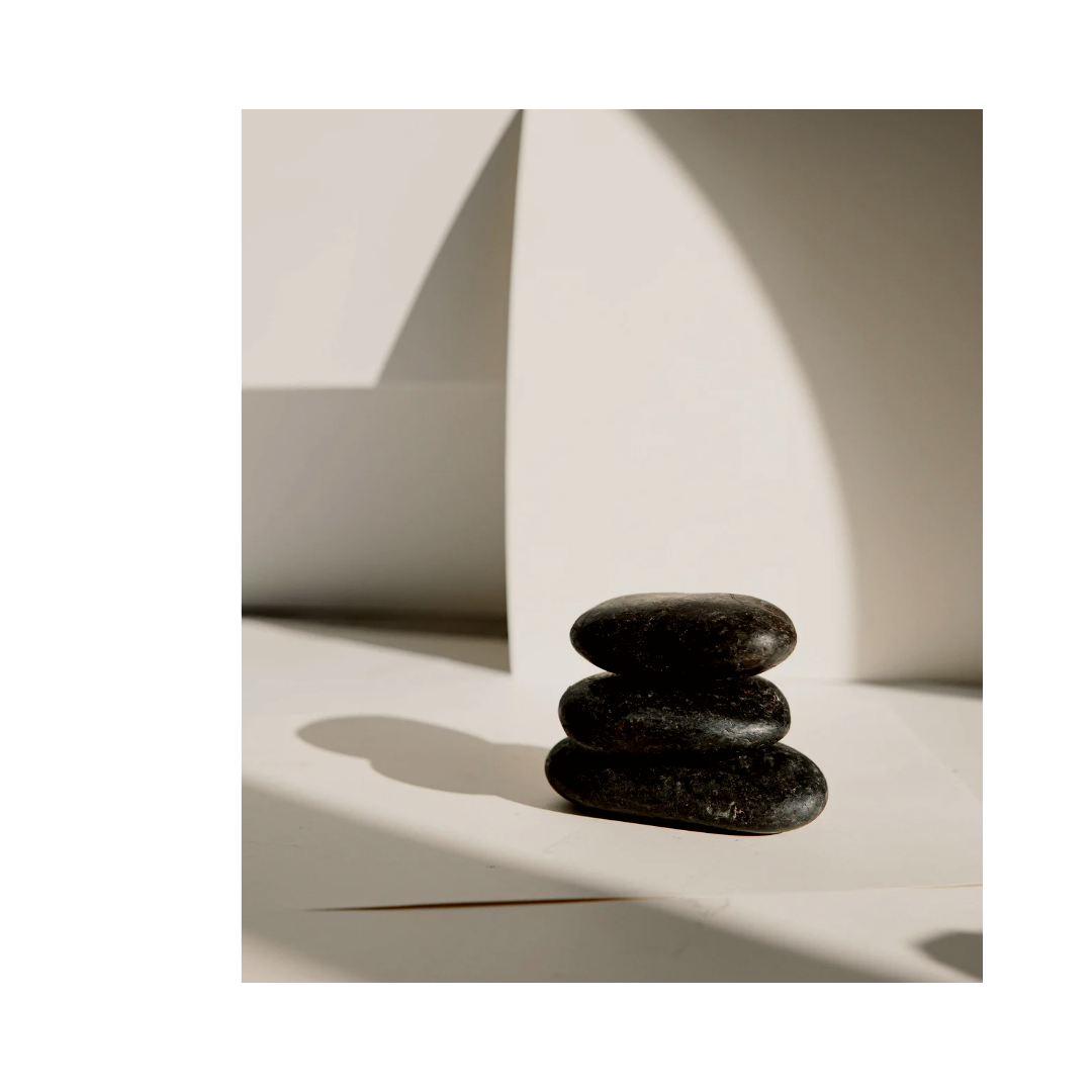 Black rocks sit against a white backdrop of light and shadows.